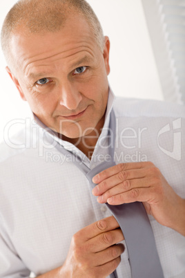 Business mature man smiling tie a tie