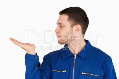 Young mechanic presenting something on his palm