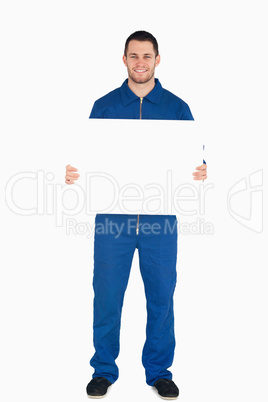 Smiling young mechanic in boiler suit holding a banner