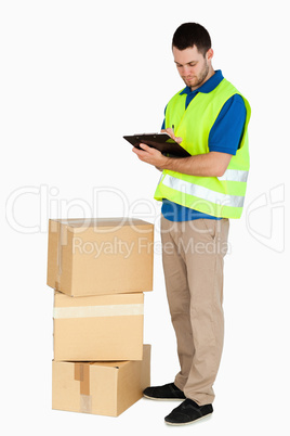 Side view of young delivery man filling in delivery note