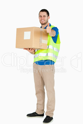 Smiling young delivery man giving approval while holding a parce
