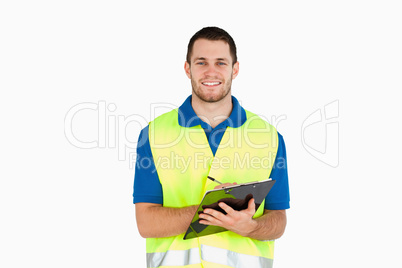 Smiling young delivery man completing delivery note