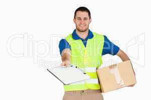 Smiling young delivery man with parcel asking for signature