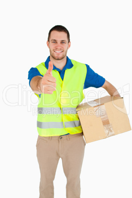 Smiling young delivery man with parcel giving thumb up