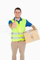 Smiling young delivery man with parcel giving thumb up