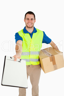 Smiling young delivery man handing over delivery note for signat