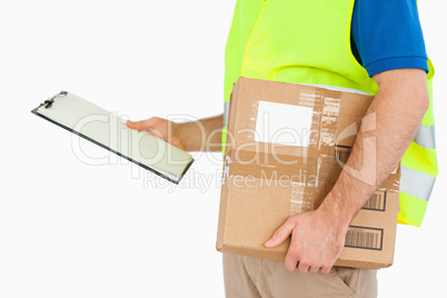 Side view of young delivery man with delivery note and parcel