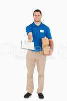 Smiling young salesman with parcel asking for signature