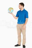 Young salesman holding globe in his palm