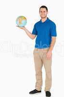 Smiling young salesman holding globe in his palm