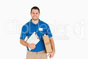 Smiling young salesman with parcel and clipboard