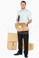 Smiling young post employee with clipboard handing over parcel