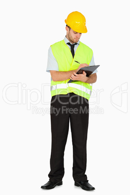 Young foreman in safety jacket taking notes on clipboard