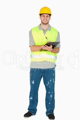 Smiling young construction worker taking notes