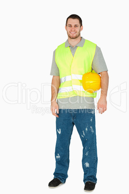 Smiling young construction worker carrying his helmet under his