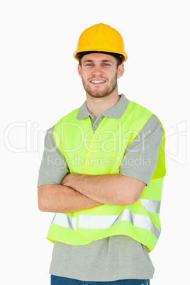 Smiling young construction worker with folded arms