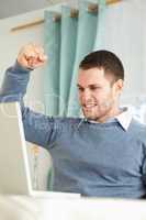 Businessman raising fist after success in his homeoffice