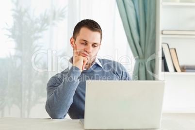 Businessman on his laptop in thoughts in his homeoffice