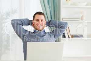 Smiling businessman leaning back in his homeoffice