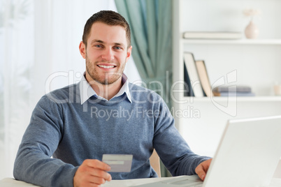 Smiling male with credit card at his laptop