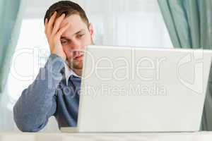 Businessman annoyed by his laptop in his homeoffice