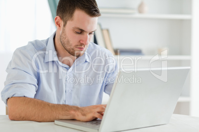 Businessman with rolled up sleeves in his homeoffice on his lapt