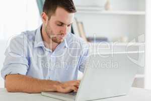Businessman with rolled up sleeves in his homeoffice on his lapt