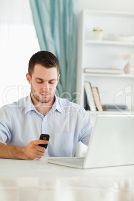 Businessman texting on his cellphone in his homeoffice