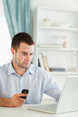 Businessman holding cellphone while typing