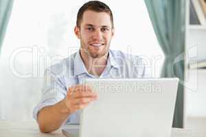 Smiling businessman sitting behind a table on his laptop