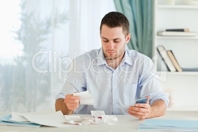 Businessman with pocket calculator checking invoices