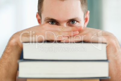 Student hiding behind a pile of books