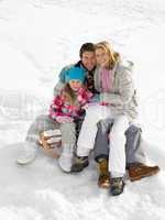 Young Family Sitting On A Sled In The Snow