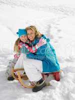 Young Mother And Daughter With A Sled In The Snow