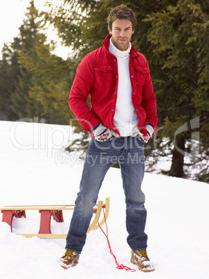 Young Man With Sled In Alpine Snow Scene