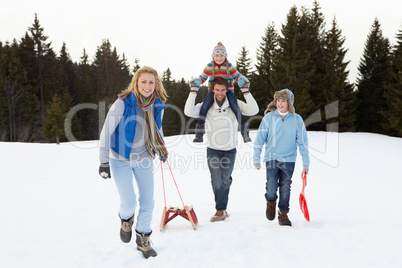 Young Family Walking Through Snow With Sled