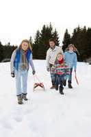 Young Family Walking Through Snow With Sled