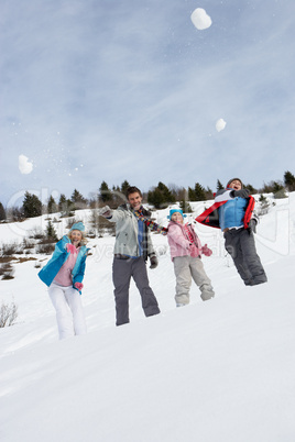 Young Family Throwing Snowballs On Winter Vacation