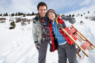 Young Father And Son In Snow With Sled