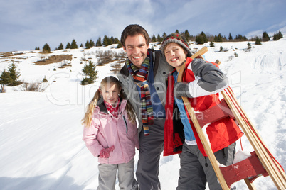 Young Father And Children In Snow With Sled