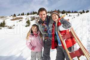 Young Father And Children In Snow With Sled