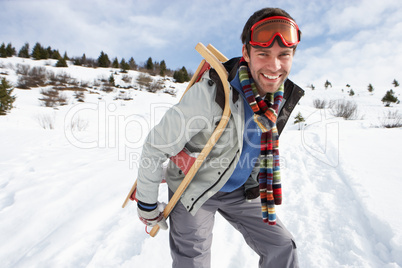Young Man Carrying Sled In Alpine Landscape
