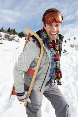 Young Man Carrying Sled In Alpine Landscape