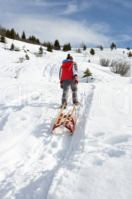 Pre-teen Boy Pulling A Sled In The Snow