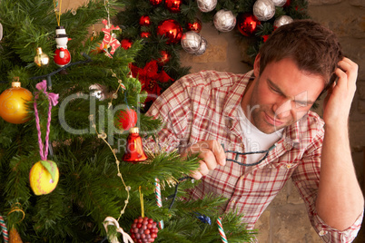 Young man trying to fix Christmas tree lights