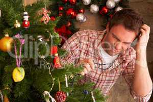 Young man trying to fix Christmas tree lights