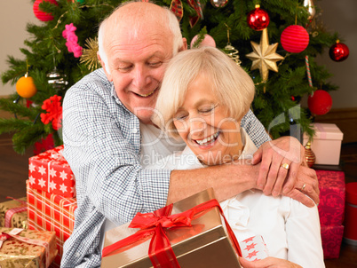 Senior couple with gifts in front of Christmas tree