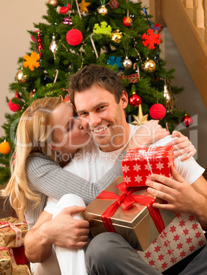 Young couple with gifts in front of Christmas tree