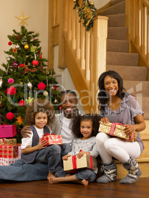 Young African American family with Christmas tree and gifts