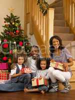 Young African American family with Christmas tree and gifts